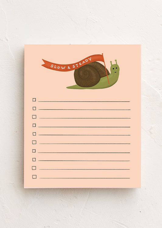 A notepad with a peach color background featuring an illustration of a snail at the top and lined space for writing.