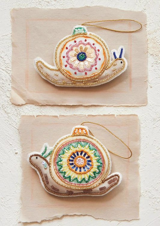 Fabric ornaments in the shape of a snail with decorative bead and sequin detailing.
