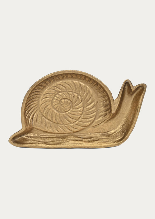 A handcrafted cast iron catchall tray in the shape of s snail in a gold finish on a white background.