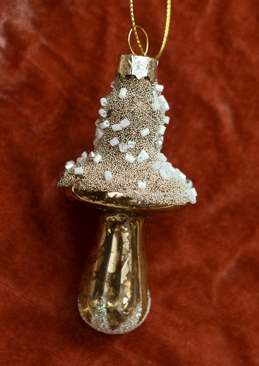 A glass ornament of gold mushroom with beaded "snow".