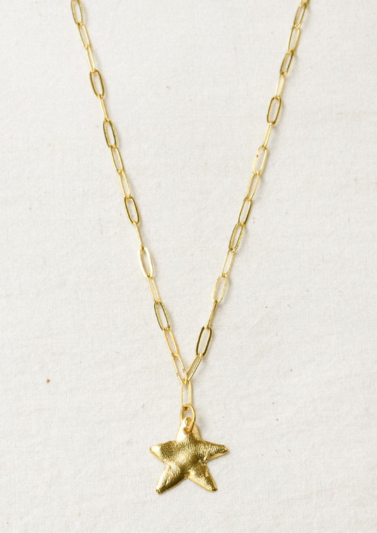 A gold paperclip chain necklace with a large star pendant.