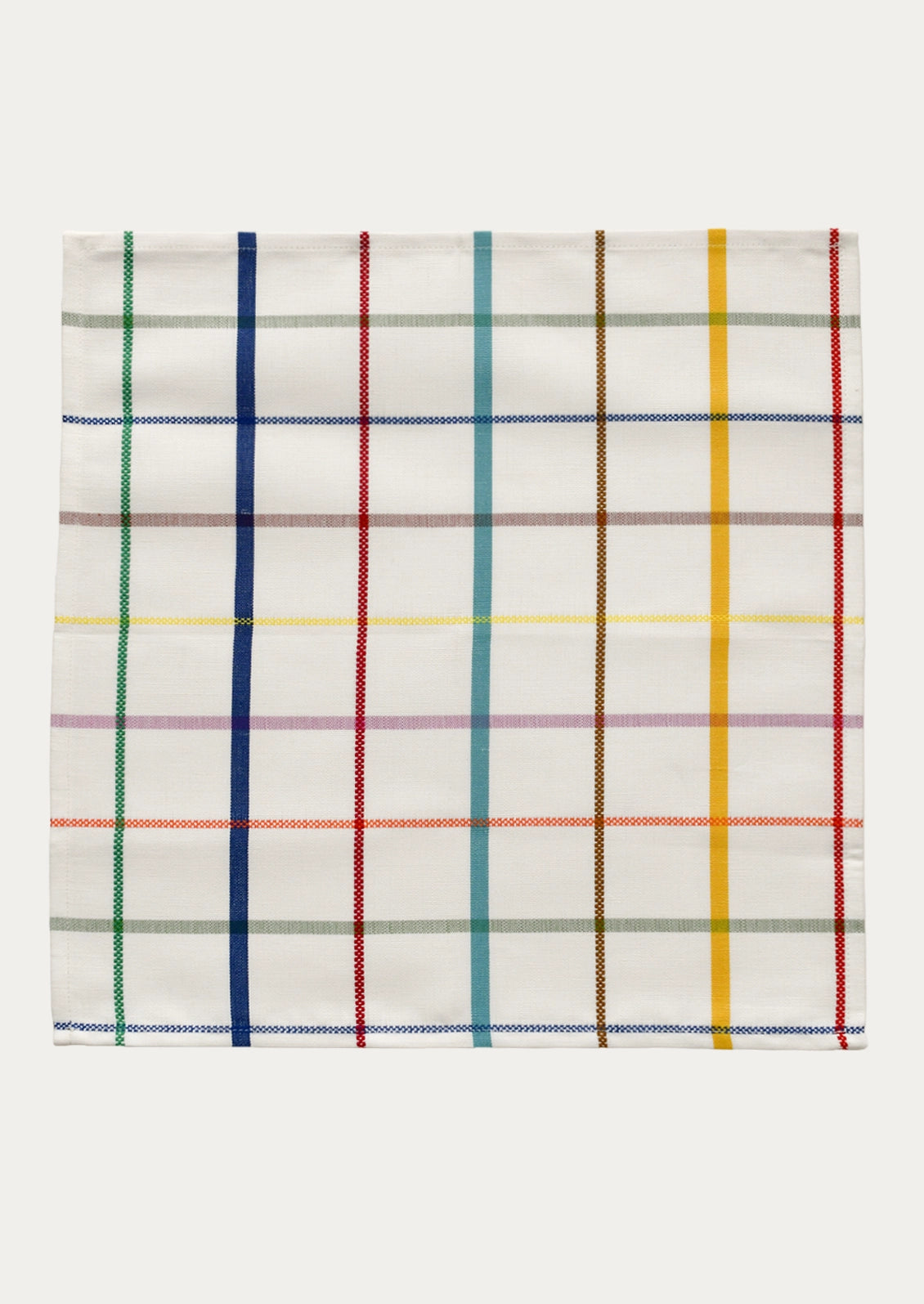 A square white woven napkin with a multicolor plaid pattern, featuring vertical stripes in green, blue, red, yellow, brown, and gray, and horizontal stripes in blue, red, yellow, and brown.