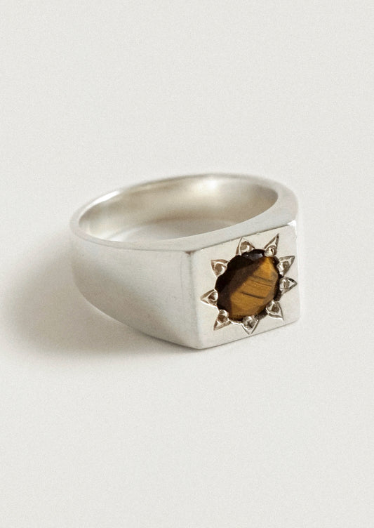 A chunky sterling silver ring with a starburst design and a brown gemstone in the center.