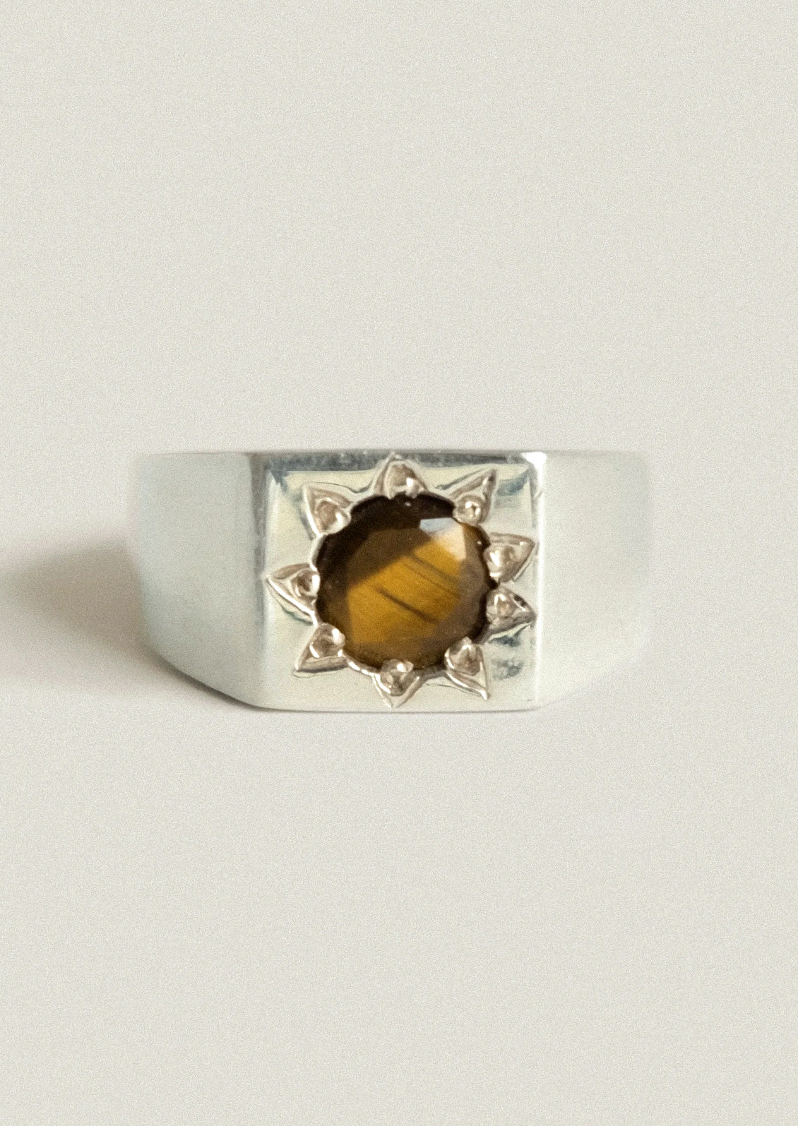 A chunky sterling silver ring with a starburst design and a brown gemstone in the center.