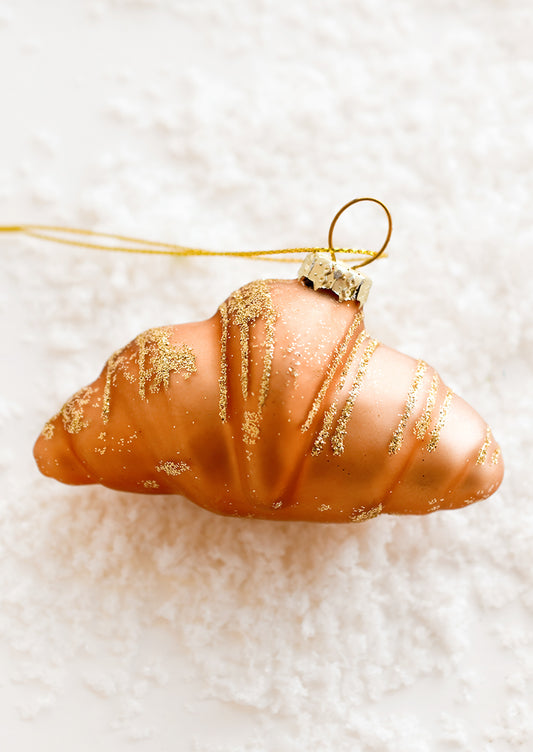A glass ornament of a plain croissant.