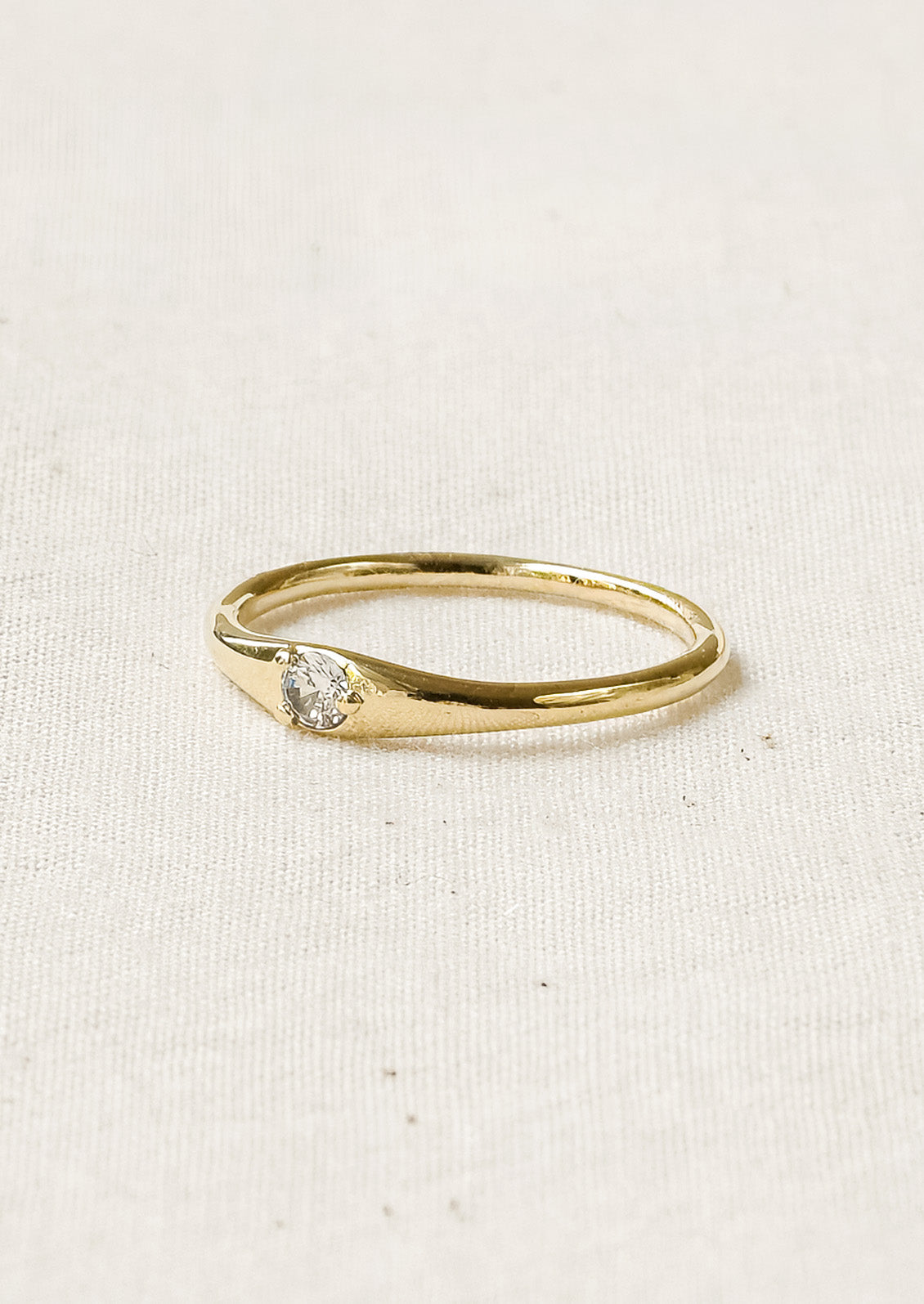 A simple gold ring with a solitaire cubic zirconia set in the center.