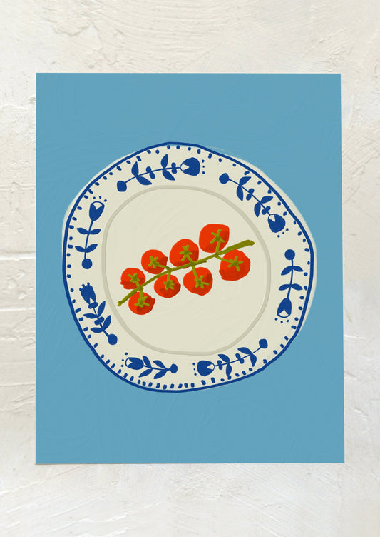 An art print with blue background and illustration of vine of cherry tomatoes on a blue and white plate.