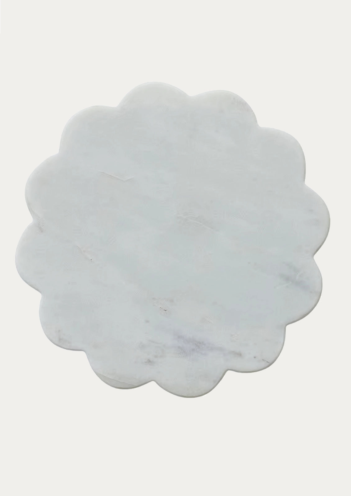 A scalloped-edge round marble trivet in a pale gray-white tone with subtle natural veining.