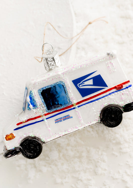 A glass holiday ornament that looks like a USPS mail truck.
