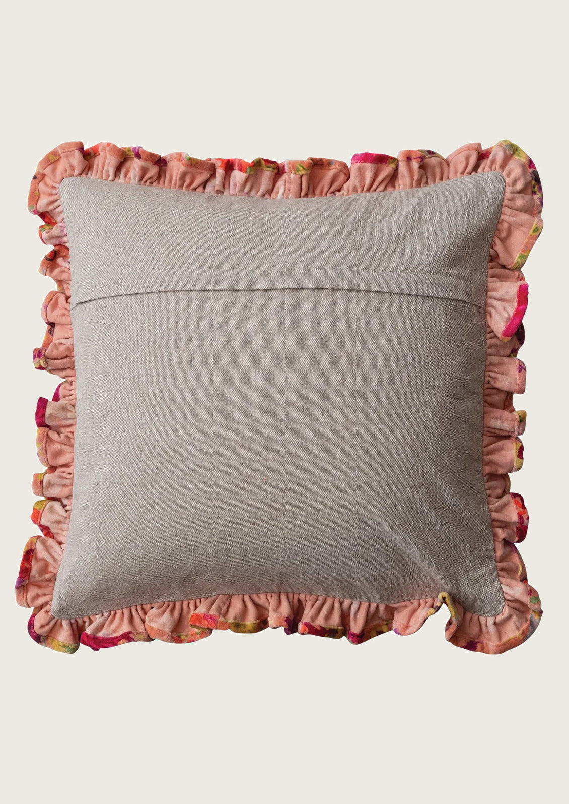 A canvas backing of a throw pillow with a dusty pink ruffled fabric border featuring a subtle multicolor floral pattern.