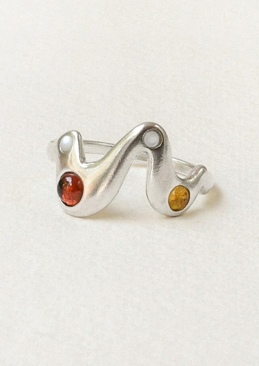 A sterling silver ring in a zigzag shape adorned with mother of pearls, garnet, and yellow citrine gems.