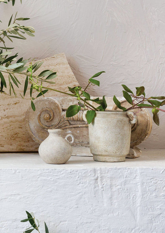 A petite ceramic bud vase in tan patina finish.