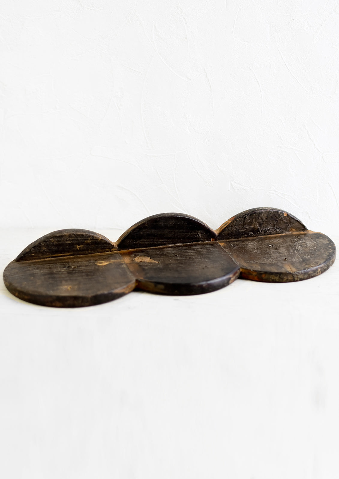 A vintage wooden wall shelf comprised of three bread boards put together.