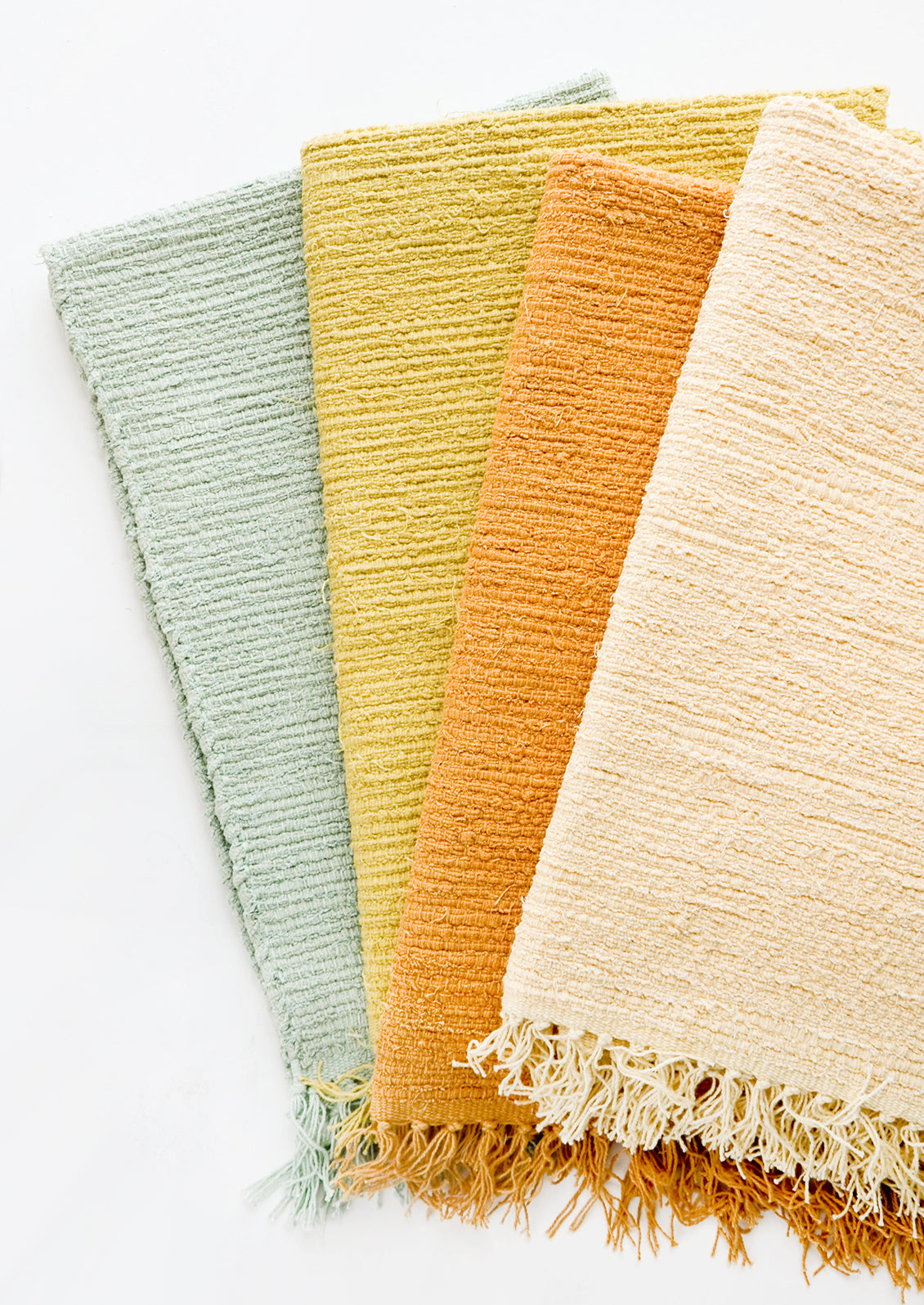 Cotton flatweave rug in solid color with slight texture, fringe trim on two ends