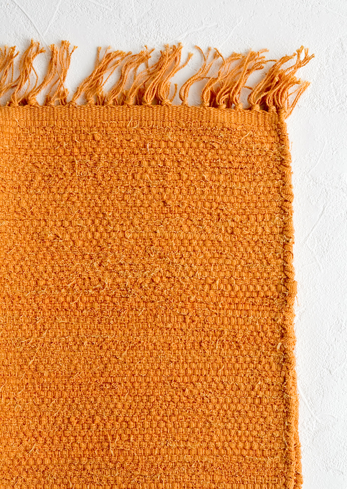 A textured cotton rug in orange rust.