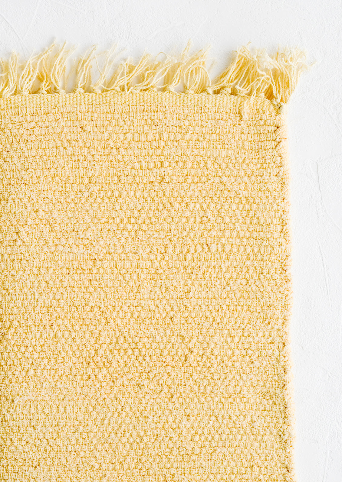 A textured cotton rug in light yellow.