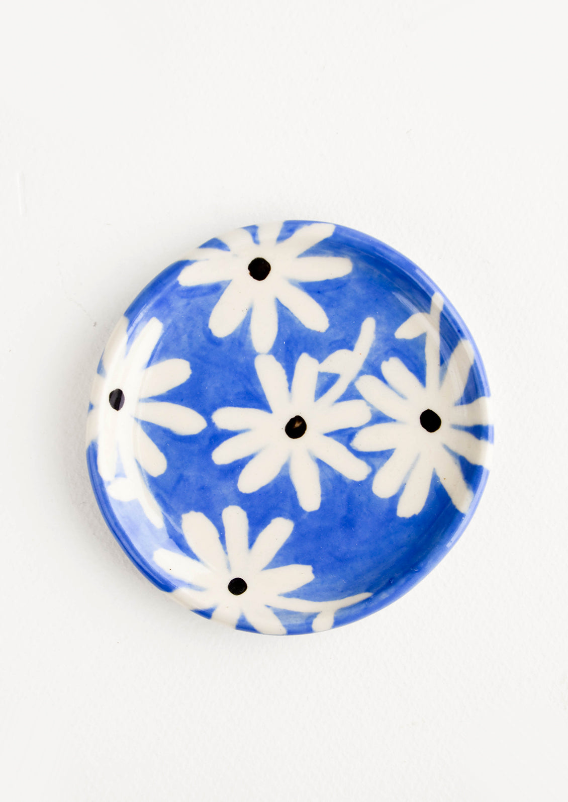 Small, round ceramic dish in blue with black and white daisies