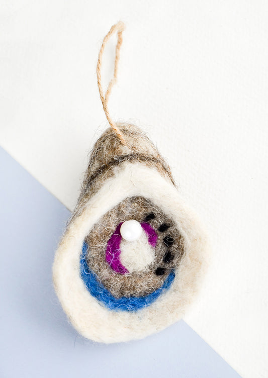 A holiday ornament in felted wool designed to look like an oyster with pearl.