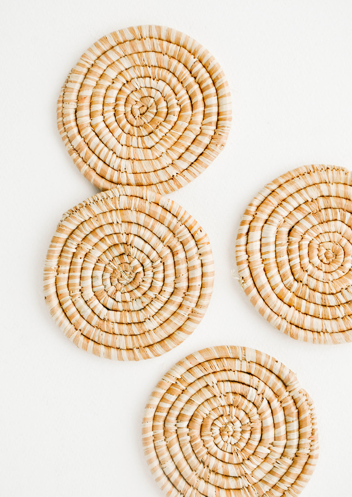 Set of 4 Round Woven Raffia Coasters in Tan and natural stripe.