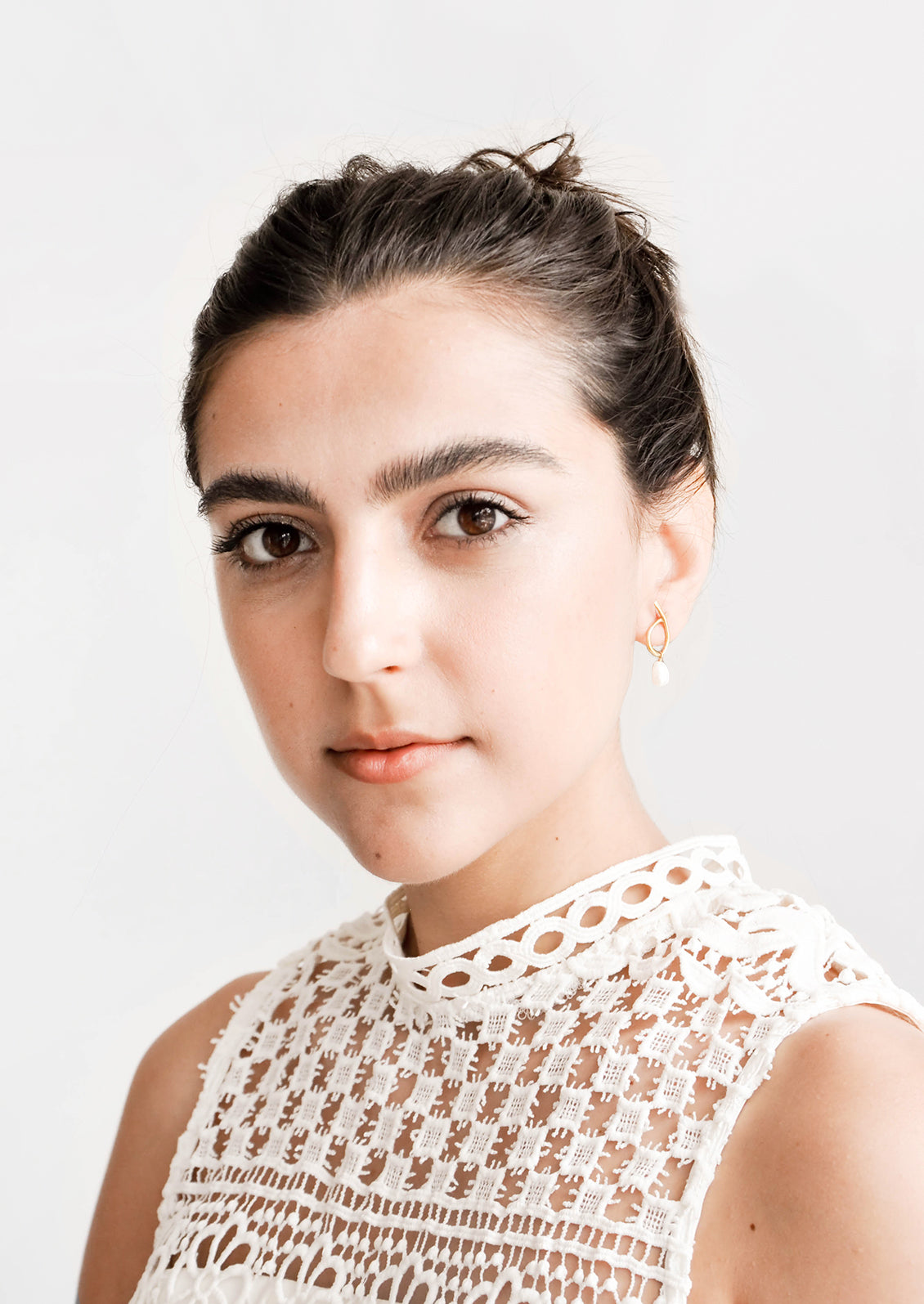 Model shot showing woman wearing earrings and white top.