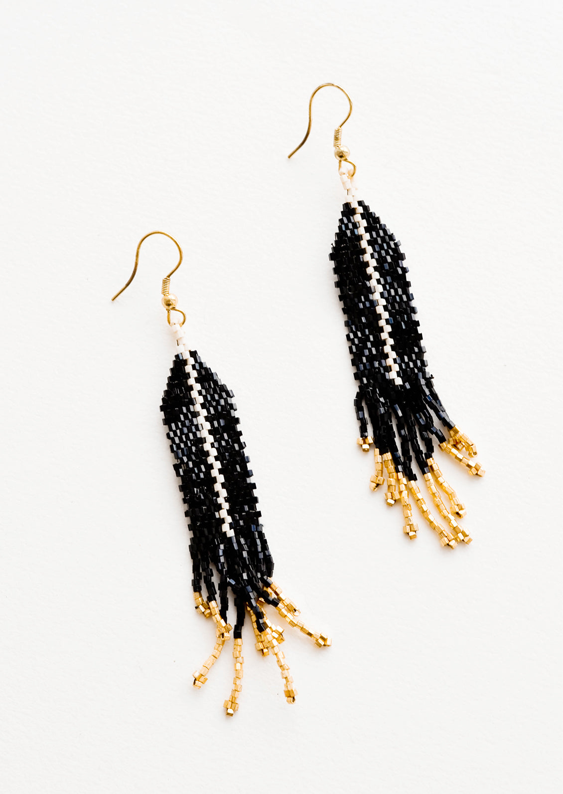 Dangling beaded earrings with black beads accented with gold bead stripe and gold bead fringe.
