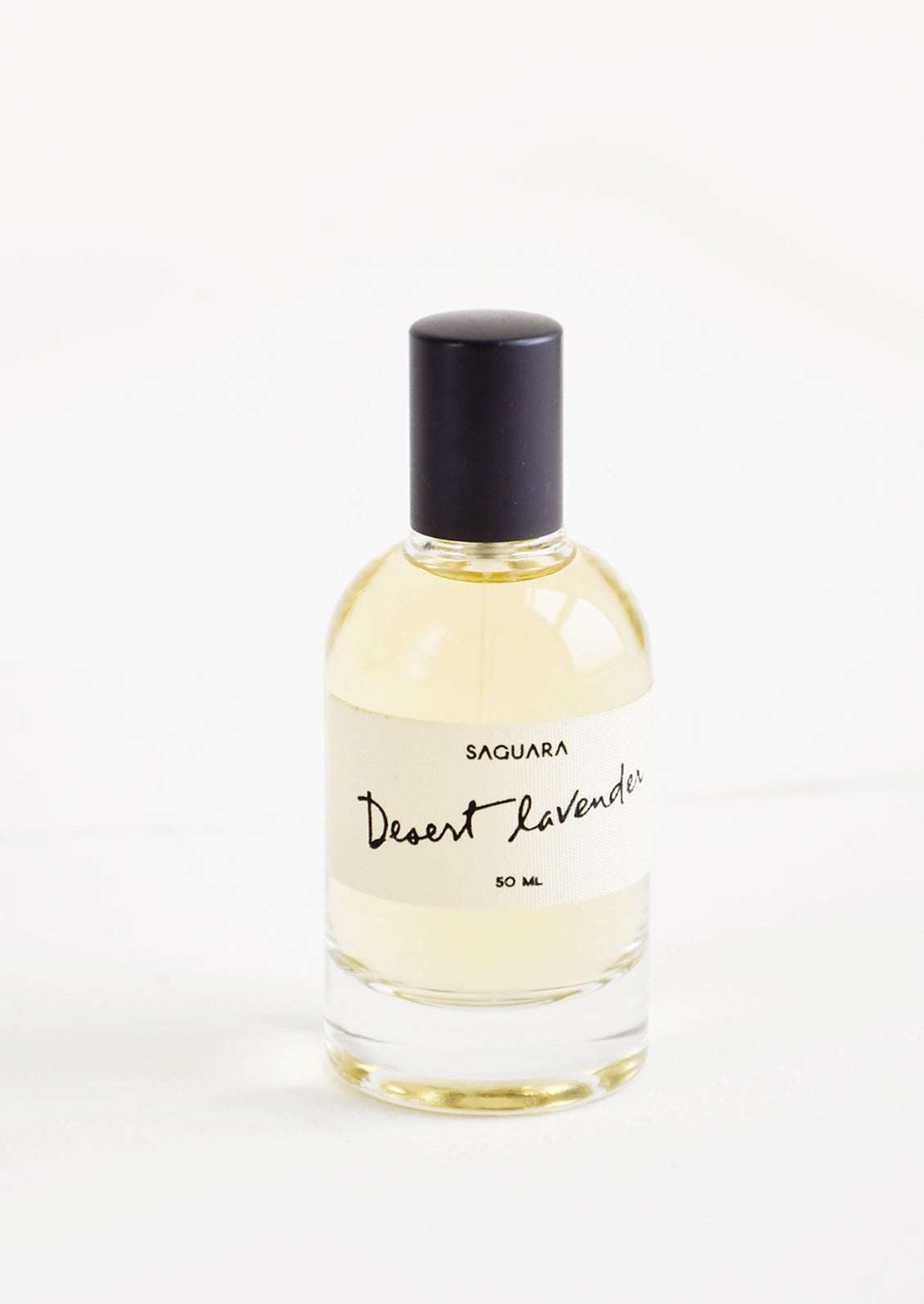 Glass perfume bottle with black cap, and white label with black script text