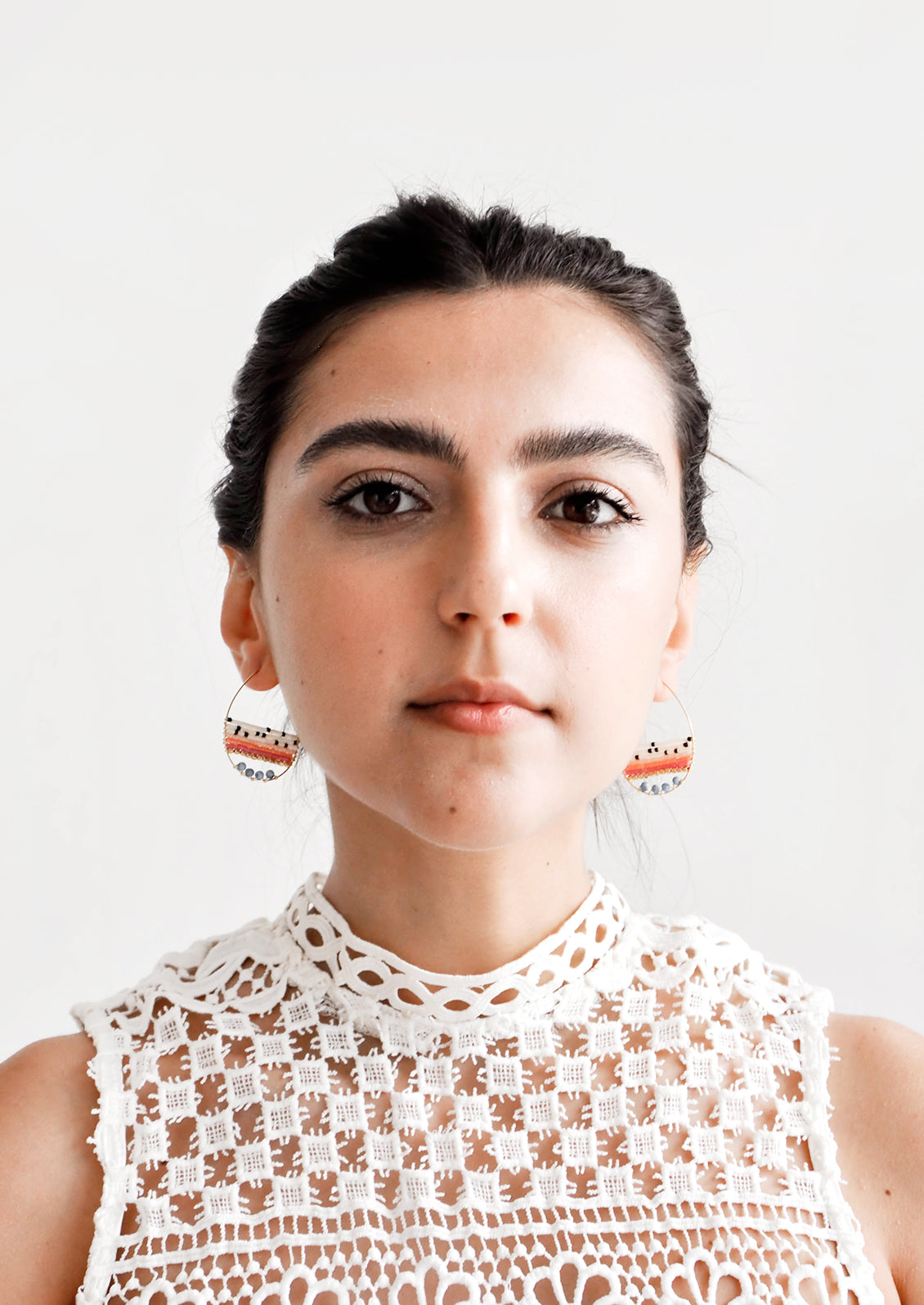Model shot showing woman wearing earrings and a white top.
