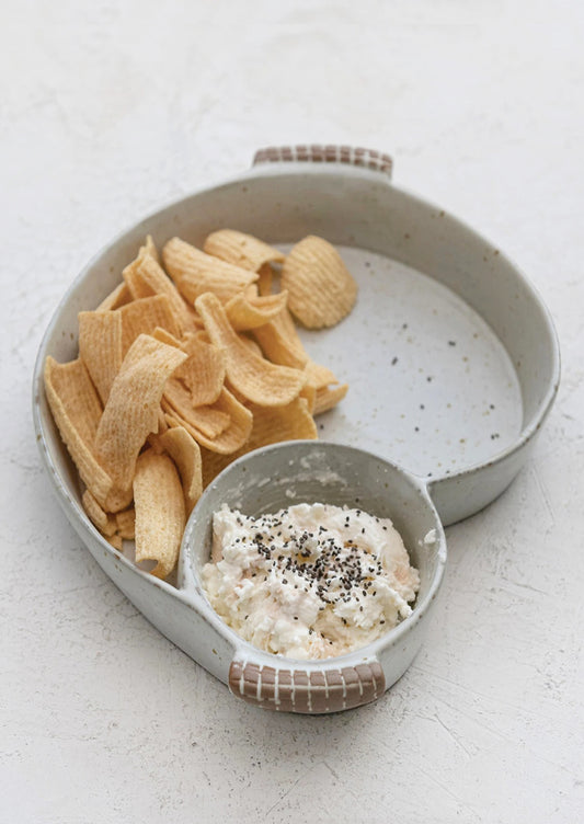 An asymmetrical serving dish with divided sections for chips and dip.