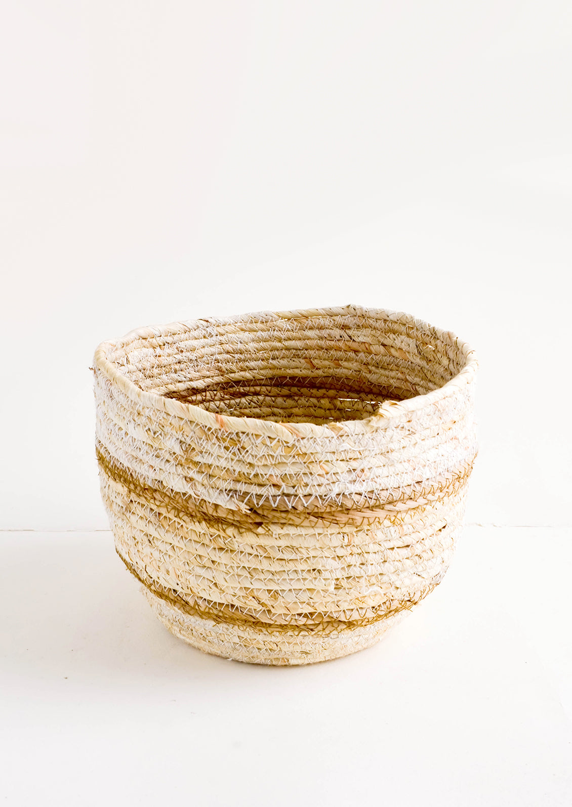 Small, round storage basket woven from natural maize fiber with tan stripes 