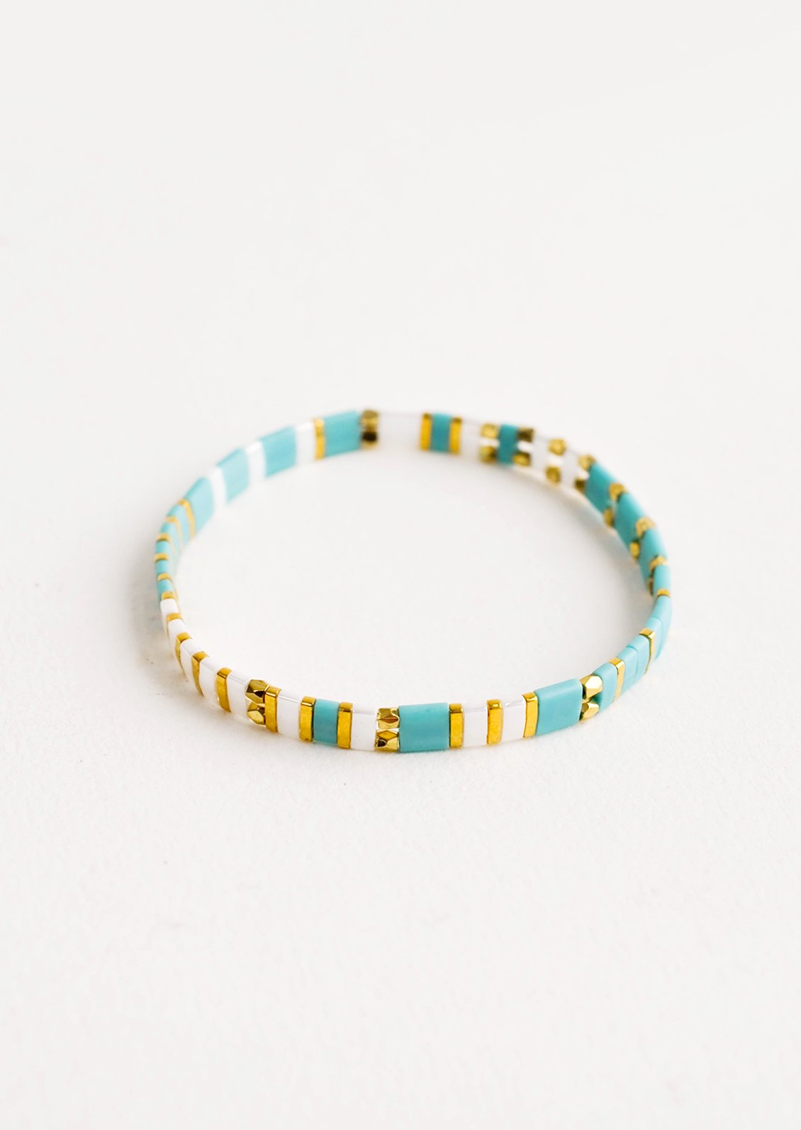 Bracelet featuring flat turquoise beads interspersed with flat gold bead on an elastic cord.