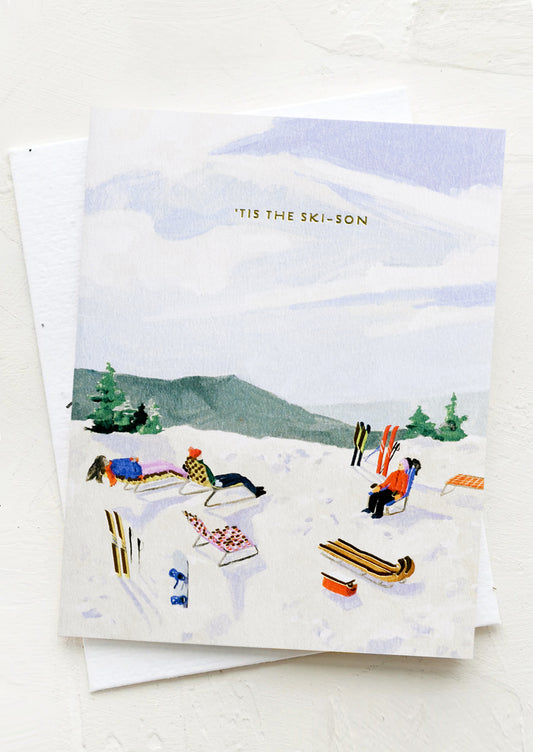 A card with illustration of skiers relaxing on a hill, text at top reads "Tis the ski-son".