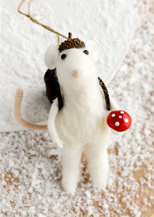 A felted holiday ornament of a mouse holding a mushroom.