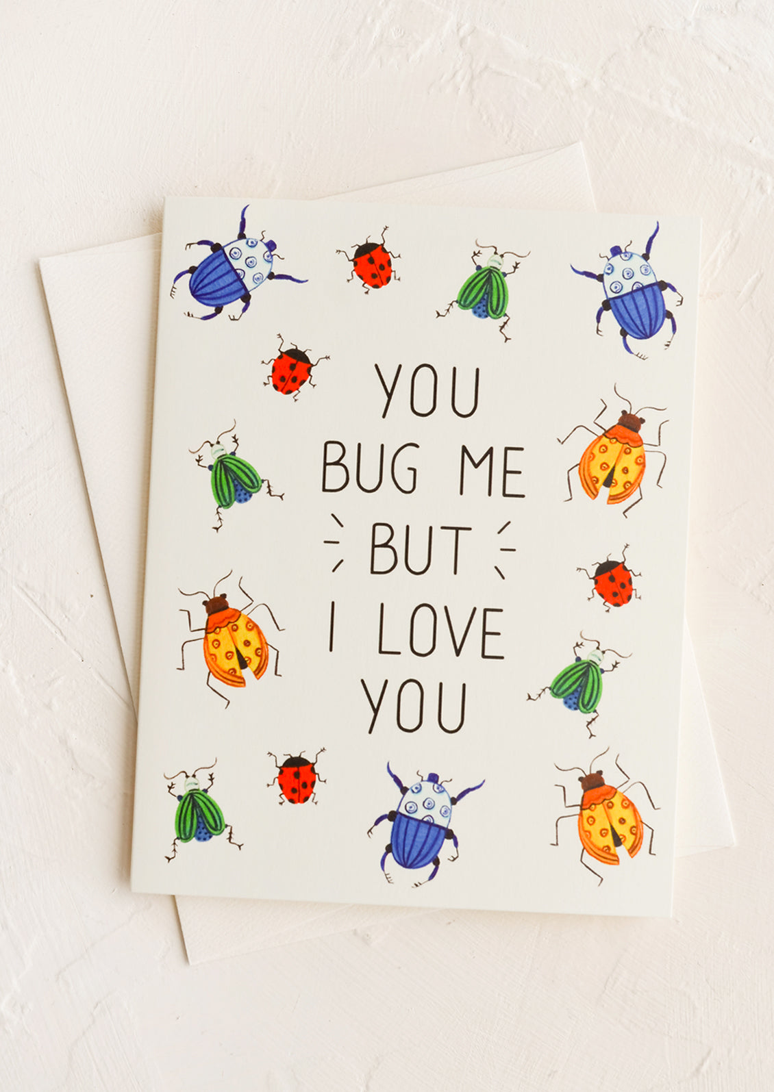 A greeting card with insect print and text reads "You bug me but I love you".